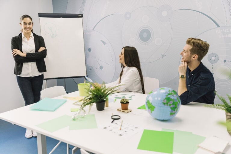 smiling-businesswoman-with-folded-hands-standing-near-flipchart-meeting_Freepik