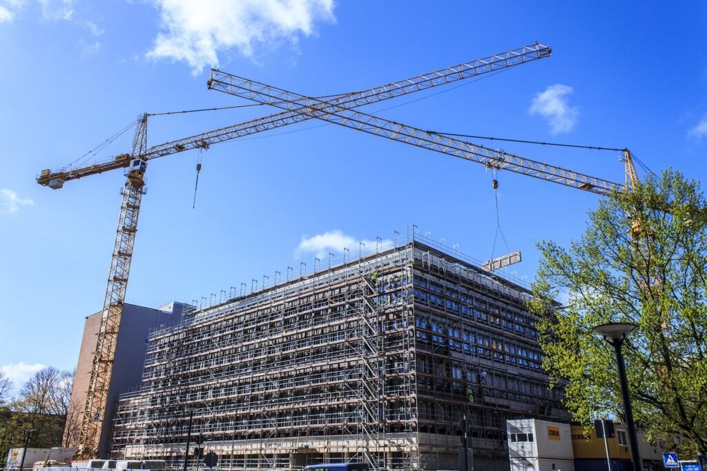 Eine Baustelle mit Gerüst und Krähnen symbolisiert den Impact nachhaltiger Entscheidungen.